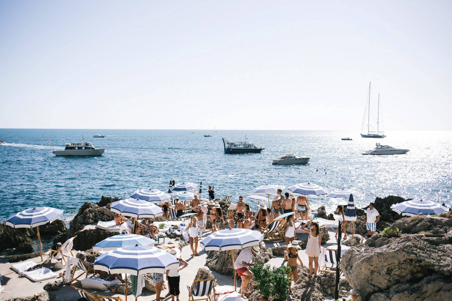 Guests under blue umbrellas La Fontelina in Capri at this Positano wedding weekend in Villa Tre Ville | Photo by Gianni di Natale