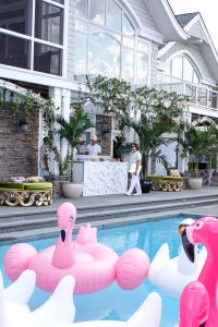 Drink bar and pool with pink flamingo and white swan floats at this South Beach-inspired first birthday pool party in the Hamptons | Photo by Cava Photo