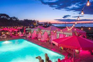 Nighttime with pink lights to create a Saint Tropez theme at this first birthday pool party in the Hamptons | Photo by Cava Photo