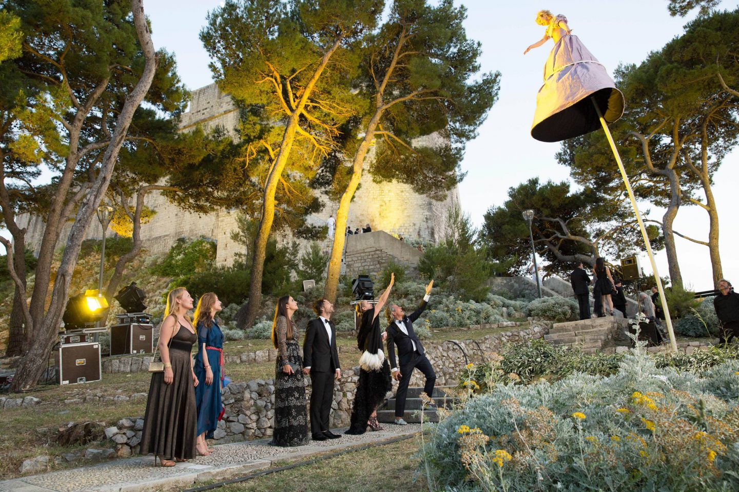 Guests and woman on stilts on their way to evening dinner at Fort Lovrijenac at this Dubrovnik wedding in Croatia | Photo by Robert Fairer