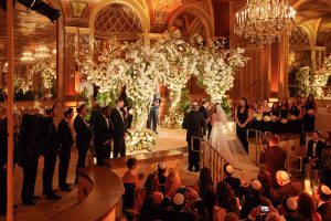 Bride and groom exchanging vows under gorgeous floral chuppah designed by Ed Libby at this classic autumn wedding at The Plaza in NYC | Photo by Christian Oth Studio