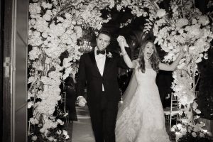 Newlyweds under floral arch designed by Ed Libby at this classic autumn wedding at The Plaza in NYC | Photo by Christian Oth Studio