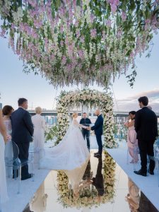 Bride and groom exchanging vows underneath cascading flowers at this Miami yacht wedding | Photo by Corbin Gurkin