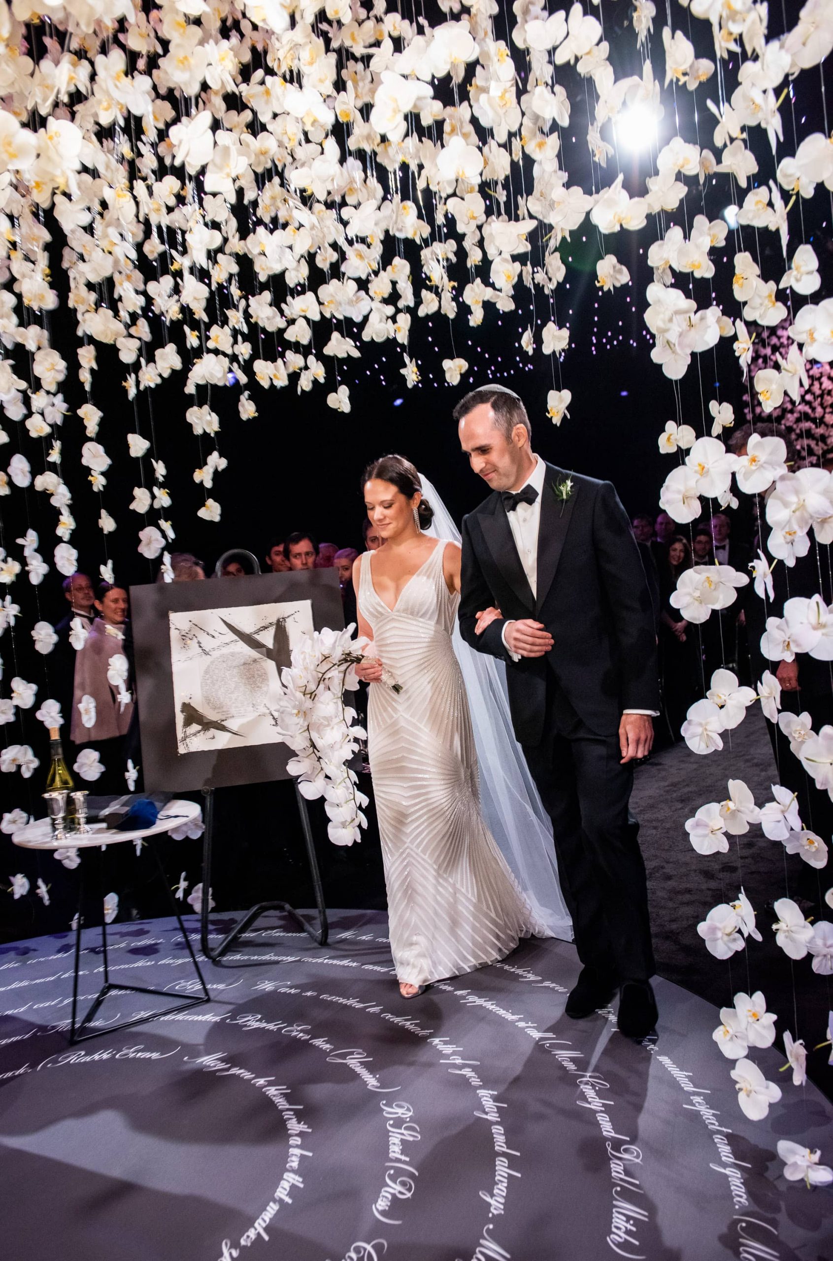 Bride and groom entering the chuppah made of hanging white orchards at this NYE wedding in New York City | Photo by Gruber Photo